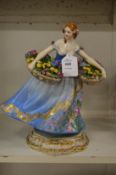 A porcelain figure of a lady holding two baskets of flowers.