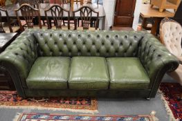 A green leather upholstered three-seater Chesterfield settee.