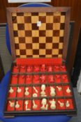 A chess board / box containing various chess pieces.