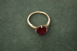 A gold ring set with a red coloured stone.