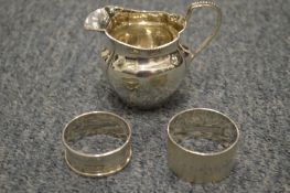 A silver jug and napkin rings.