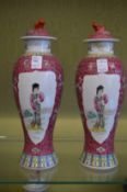 A pair of Chinese Famille Rose baluster shaped vases and covers decorated with female figures.