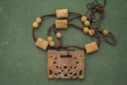 A carved and pierced pendant with corded necktie having carved beaded decoration.