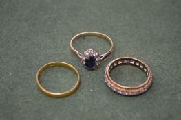 A gold, diamond and sapphire ring, a gold wedding band and an eternity ring.