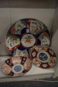 A large Japanese Imari porcelain charger and two similar items.