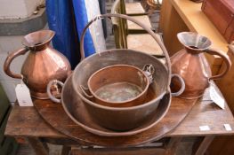 A pair of old copper harvest jugs and three preserve pans.