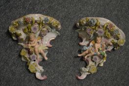 A Capodimonte style pair of porcelain wall brackets with floral encrusted and cherub decoration.