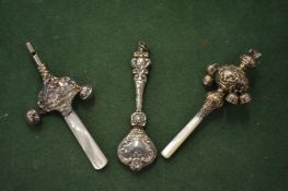 Three silver rattles, two with mother-of-pearl handles and bells.