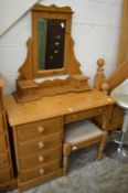 A pine dressing table with mirror and stool.