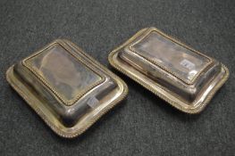 A pair of plated entree dishes and covers.