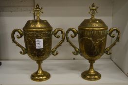 A pair of Indian engraved brass twin handled pedestal cups and covers.