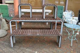 A stylish slatted hardwood and metal framed patio with bench sets and pair of matching stools/