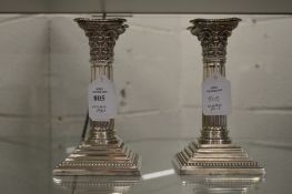 A pair of plated Corinthian column style candlesticks.