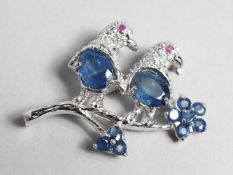 A SILVER, RUBY EYED AND SAPPHIRE BIRD BROOCH.