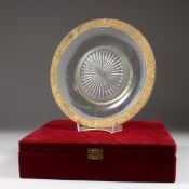 A CIRCULAR CUT GLASS DISH with a gilt decorated moulded rim, in a red velvet box. 10ins diameter.