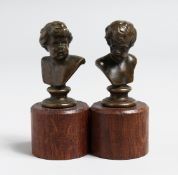 JEAN QUI. A SMALL PAIR OF BARBEDIENNE BRONZE BUSTS. 2ins high, on wooden bases.