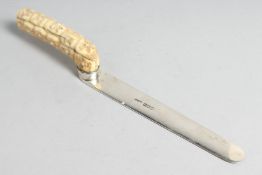 A VICTORIAN SILVER LETTER OPENER with carved ivory handle of many heads. 10ins long