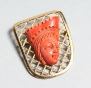 AN 18K GOLD BROOCH with a coral Egyptian head, 4cm long x 3cm wide.