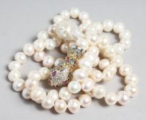 A STRING OF PEARLS with sapphire set snake head clasp.