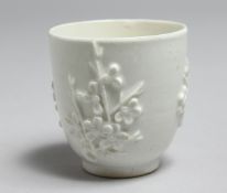 AN 18TH CENTURY BOW BLANC DE CHINE COFFEE CUP decorated with applied prunus sprigs.