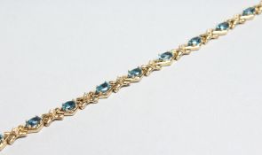 A 14CT GOLD BLUE TOPAZ AND DIAMOND BRACELET.