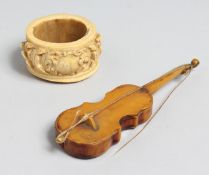 A EUROPEAN CARVED IVORY SERVIETTE RING, 2ins diameter and a miniature violin (2).