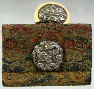 A JAPANESE WOVEN CLOTH PURSE, with embossed silver dragon mount and large ivory manju netsuke toggle
