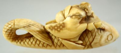 A JAPANESE CARVED IVORY NETSUKE of a seated deity on the back of a giant fish, signed to the base,