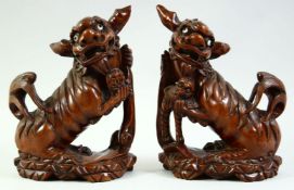 A PAIR OF CHINESE CARVED HARDWOOD DOGS OF FO FIGURES, each with inlaid eyes, both 24.5cm high.