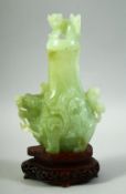 A CHINESE CARVED JADE VASE AND COVER on a fitted hardwood stand, the vase carved with foo dogs,