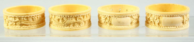 A SET OF FOUR CHINESE CARVED IVORY NAPKIN RINGS, each carved with a dragon, 5.5cm diameter.