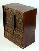 A SMALL JAPANESE HARDWOOD CABINET, onlaid with various metal menuki, comprising two sliding doors,
