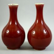 A PAIR OF CHINESE SANG DE BOEUF BOTTLE VASES, (rims af), 23cm high.