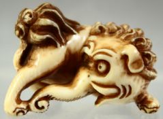 A JAPANESE CARVED IVORY NETSUKE of an elephant like beast, signed to the reverse, 4cm long.
