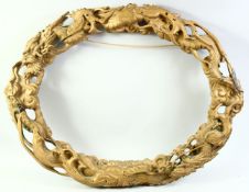 A LARGE CARVED WOOD OVAL SHAPE DRAGON FRAME, 77cm x 64cm.