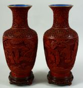 A PAIR OF CHINESE CINNABAR LACQUER VASES on hardwood stands, with relief panels of figures in a