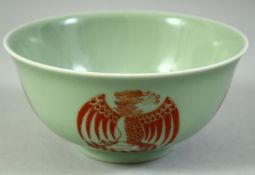 A CHINESE CELADON GLAZED PORCELAIN BOWL, painted in copper red with phoenix, the base with siz