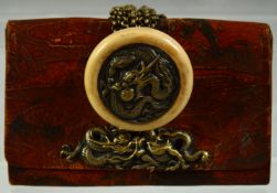 A JAPANESE LEATHER PURSE mounted with embossed metal dragon and ivory manju netsuke toggle with