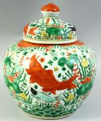 A CHINESE WUCAI PORCELAIN JAR AND COVER, painted with fish and algae, the base with six character