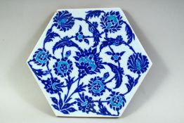 A TURKISH IZNIK GLAZED POTTERY HEXAGONAL TILE, decorated with floral motifs, 25.5cm x 22cm.
