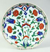 A TURKISH IZNIK GLAZED POTTERY PLATE, decorated with central floral spray, 31cm diameter.