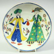 A SMALL TURKISH KUTAHYA DISH, decorated with two figures, 15.5cm diameter.