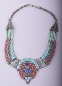 A TURQUOISE AND CORAL INSET WHITE METAL NECKLACE.