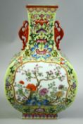 A CHINESE GREEN GROUND FAMILLE ROSE PORCELAIN VASE with moulded twin handles, the body decorated