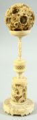 A CHINESE CARVED IVORY PUZZLE BALL ON STAND, the carved floral ball elevated upon a finely carved