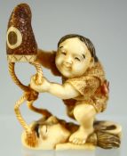 A GOOD SMALL JAPANESE CARVED IVORY OKIMONO of a child lifting a hat off of a noh mask, signed, 5.5cm
