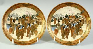 A SMALL PAIR OF JAPANESE SATSUMA DISHES, each painted with many figures in a landscape scene, with
