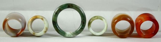FIVE GOOD AGATE AND JADE / JADEITE ARCHER'S RINGS, together with a larger jade / jadeite ring, (6).