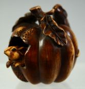 A SMALL JAPANESE WOOD CARVING / NETSUKE of a pumpkin with two mice, one reticulated mouse emerging