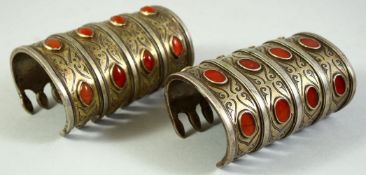 TWO ISLAMIC TURKMAN METAL CUFF BRACELETS, inset with carnelian stones, each 11cm long.